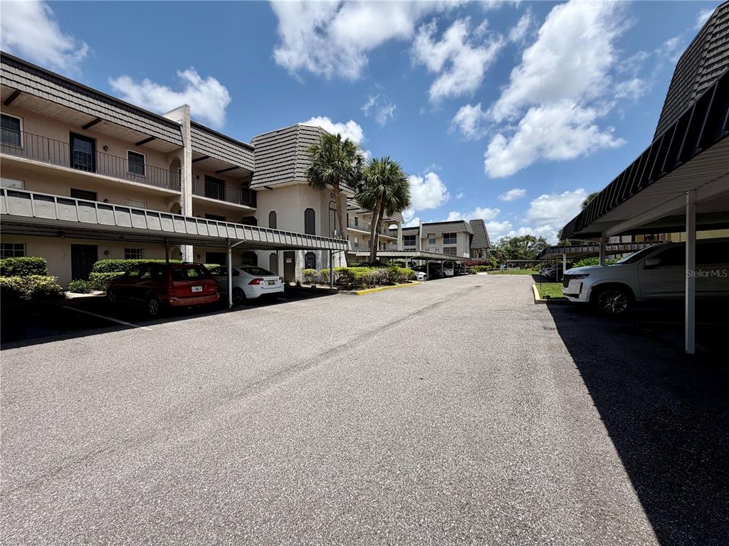 An outdoor parking lot with covered carports sits between two multi-story apartment buildings — 8703 BARDMOOR BOULEVARD UNIT 102, SEMINOLE, FL