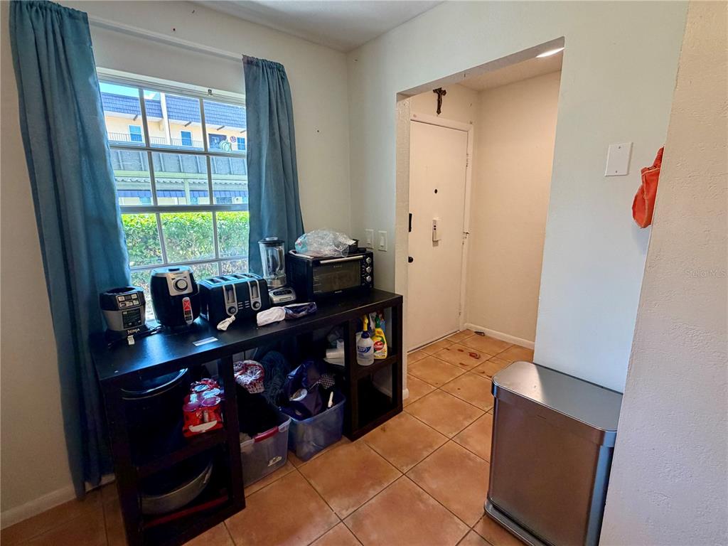 A kitchen area features a black console table with small appliances, tile flooring, and a window — 8703 BARDMOOR BOULEVARD UNIT 102, SEMINOLE, FL