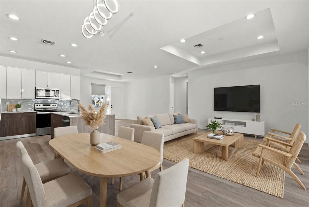 An open-concept living and dining area features light wood flooring, white cabinetry, and modern furniture — 2711 ATWATER DRIVE, NORTH PORT, FL