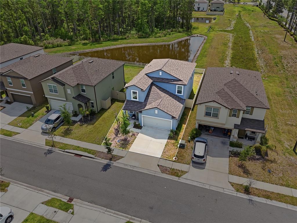An aerial view shows a blue suburban house with a garage and a backyard pond — 2256 TENEROC TRAIL, LAKELAND, FL