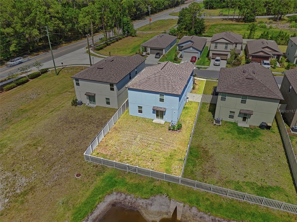 An aerial view shows a light blue two-story house with a fenced backyard and pond — 2256 TENEROC TRAIL, LAKELAND, FL