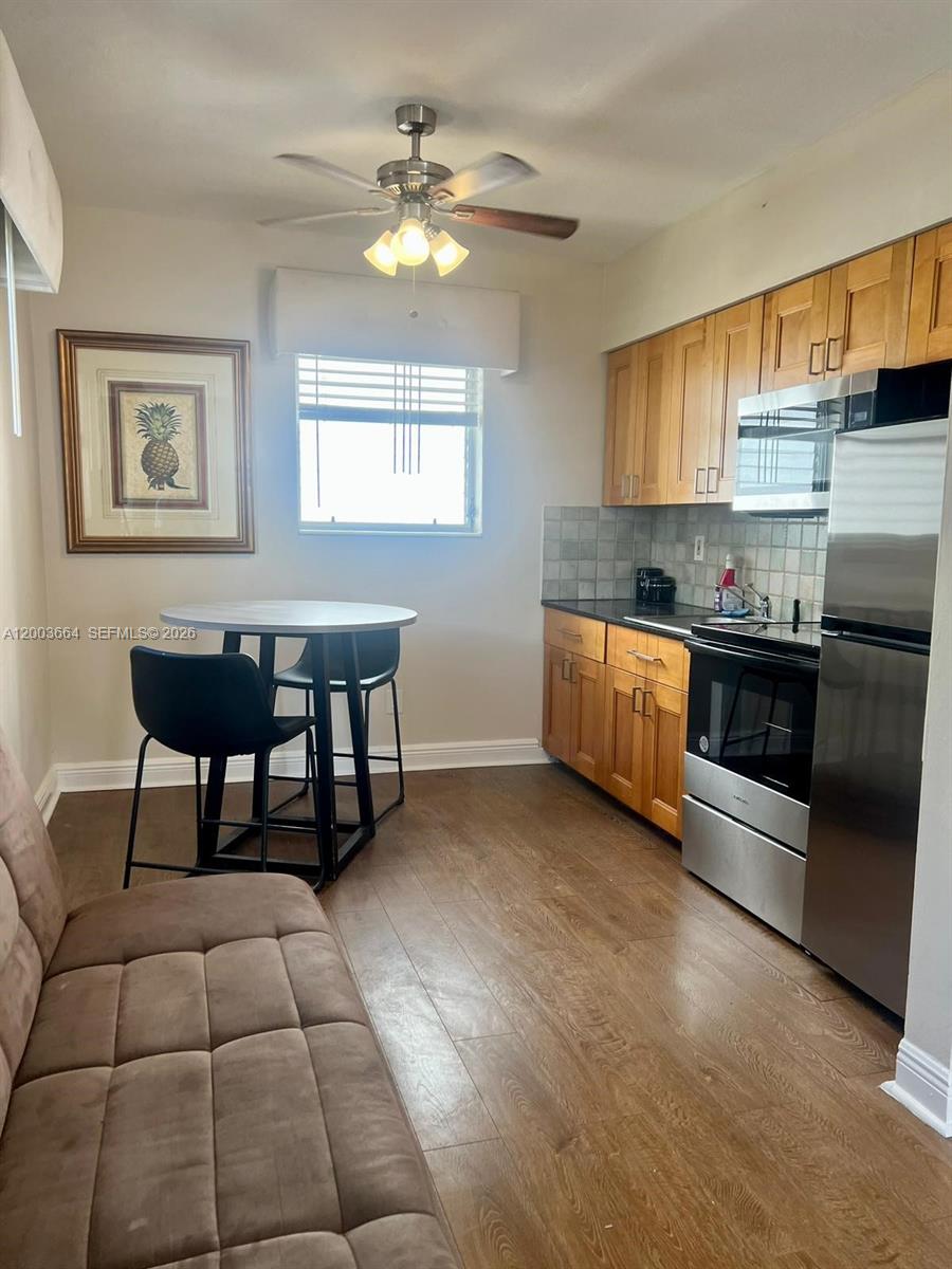 This kitchen features wood cabinets, stainless steel appliances, a dining table, and wood-look flooring — 740 Michigan Ave # 10, Miami Beach FL 33139, MIAMI BEACH, FL