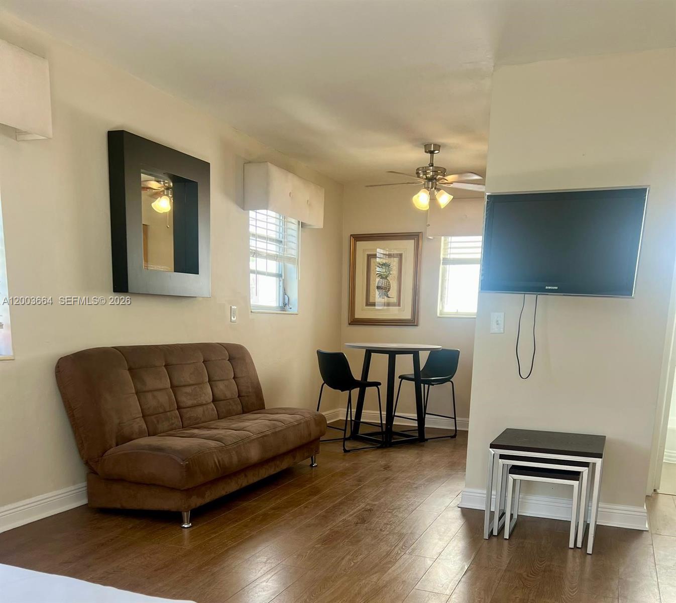 This living area features a brown sofa, a small dining table, and a wall-mounted television — 740 Michigan Ave # 10, Miami Beach FL 33139, MIAMI BEACH, FL