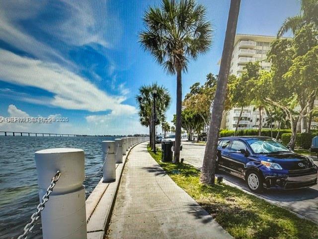 A paved walkway runs along a waterfront with a parked car and palm trees — 1420 Brickell Bay Dr # 1107C, Miami FL 33131, MIAMI, FL