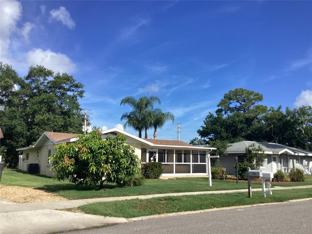 A single-story house with a screened-in front porch and a large tree in the yard — 710 50TH STREET COURT W, BRADENTON, FL
