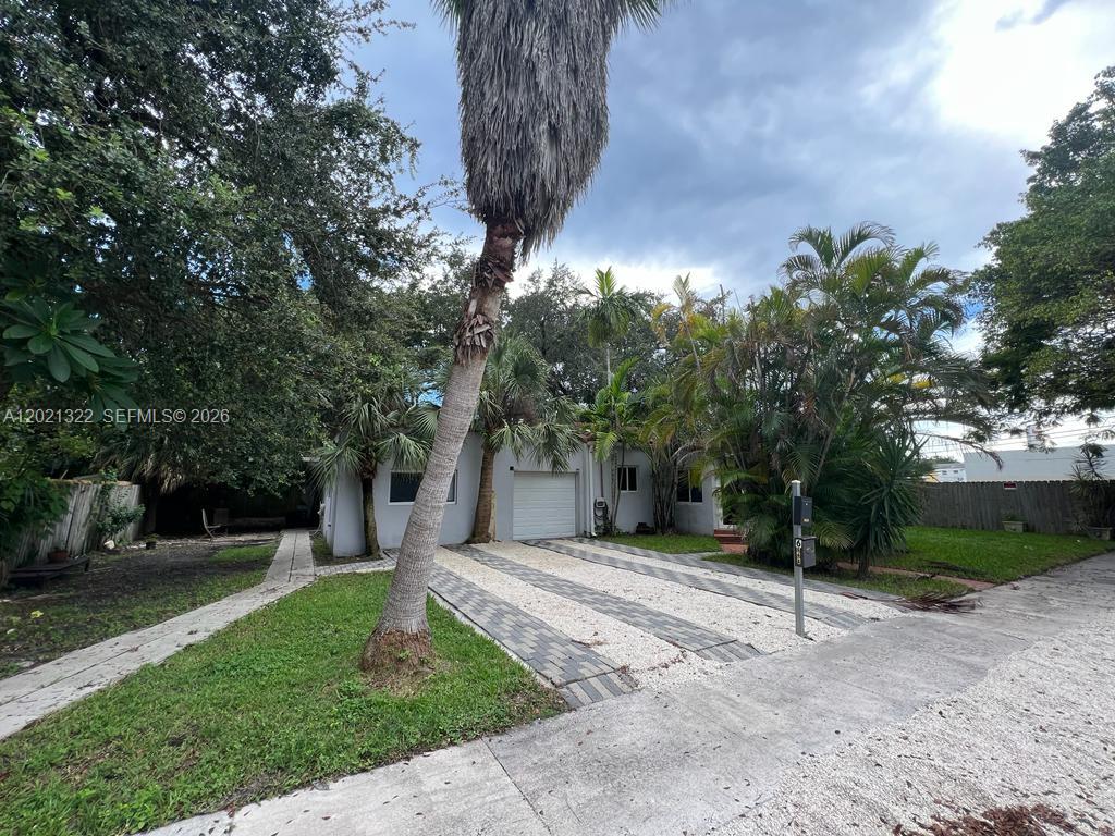 A single-story house with a white garage door, gravel driveway, and mature palm trees — 644 NE 82nd Ter # 1, Miami FL 33138, MIAMI, FL