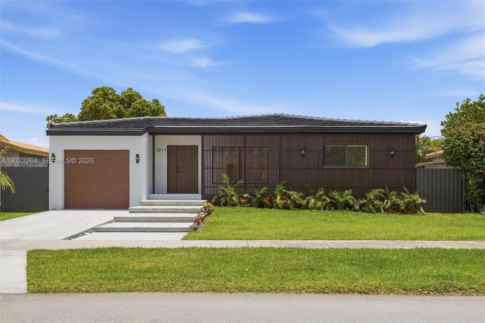 A single-story house features a white garage, wood-slat siding, and a concrete walkway — 1911 SW 18th Ave, Miami FL 33145, MIAMI, FL