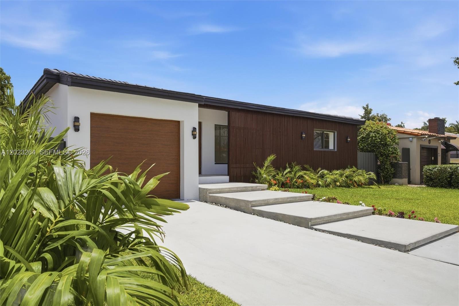 A modern single-story house features a wood-slatted facade, a garage, and concrete steps — 1911 SW 18th Ave, Miami FL 33145, MIAMI, FL