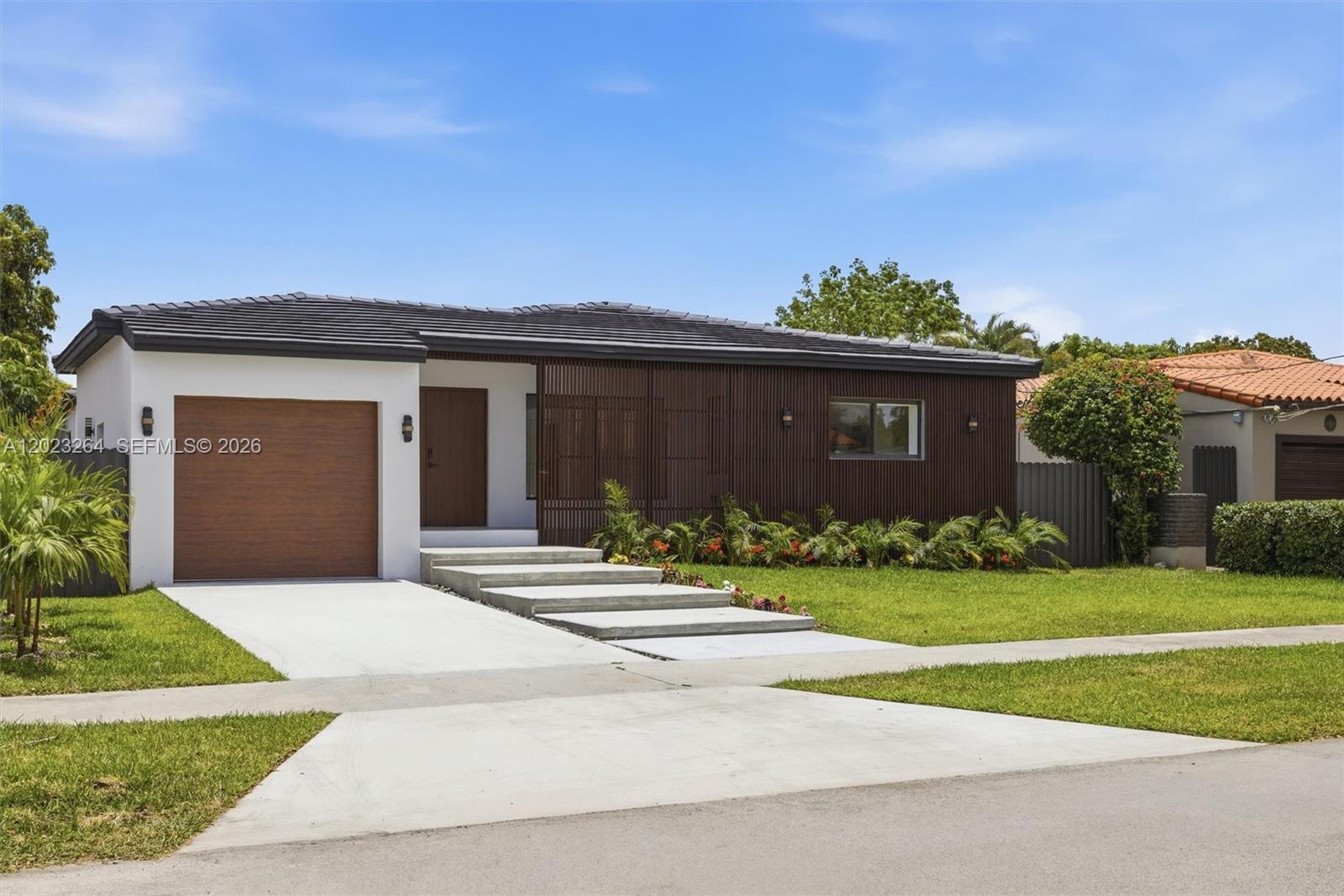 A modern single-story house features a wood-slatted facade, a garage, and concrete entry steps — 1911 SW 18th Ave, Miami FL 33145, MIAMI, FL