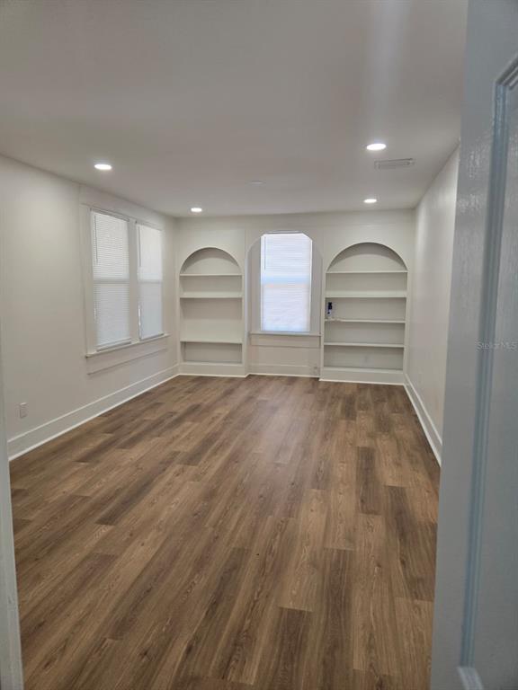 An empty room features wood-look flooring, recessed lighting, and built-in arched shelving units — 709 E JAMES STREET, TAMPA, FL