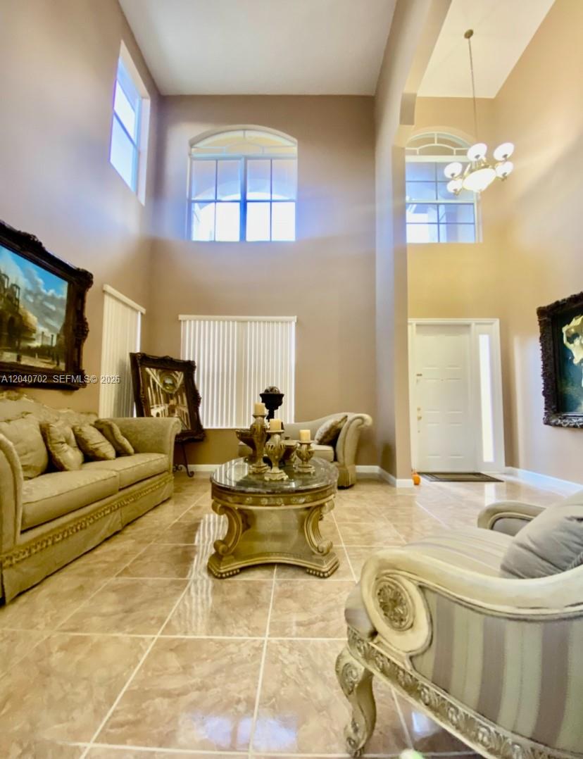 A high-ceilinged living room features tile flooring, ornate furniture, and large arched windows — 13187 SW 26th St, Miramar FL 33027, MIRAMAR, FL