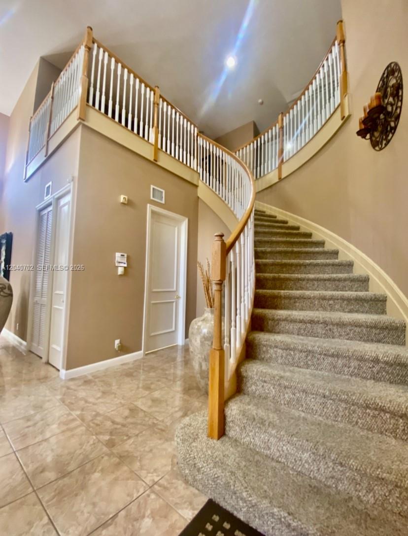A curved carpeted staircase with a white railing leads to a second-floor landing — 13187 SW 26th St, Miramar FL 33027, MIRAMAR, FL