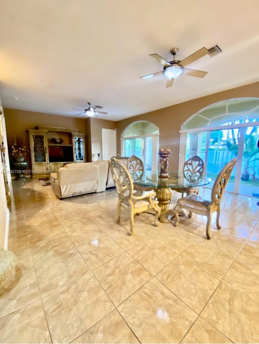 A dining area with a glass table and chairs sits adjacent to a living room — 13187 SW 26th St, Miramar FL 33027, MIRAMAR, FL