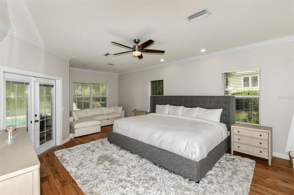 A spacious bedroom features a large gray upholstered bed, white sofa, and hardwood flooring — 1350 N CIRCUS TERRACE, HERNANDO, FL