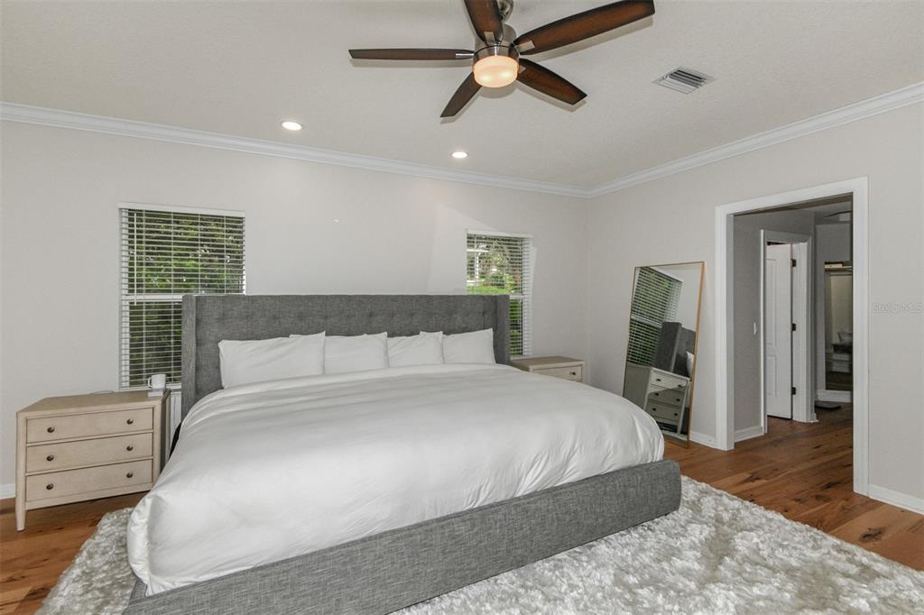 A bedroom features a gray upholstered bed, white bedding, a ceiling fan, and hardwood floors — 1350 N CIRCUS TERRACE, HERNANDO, FL
