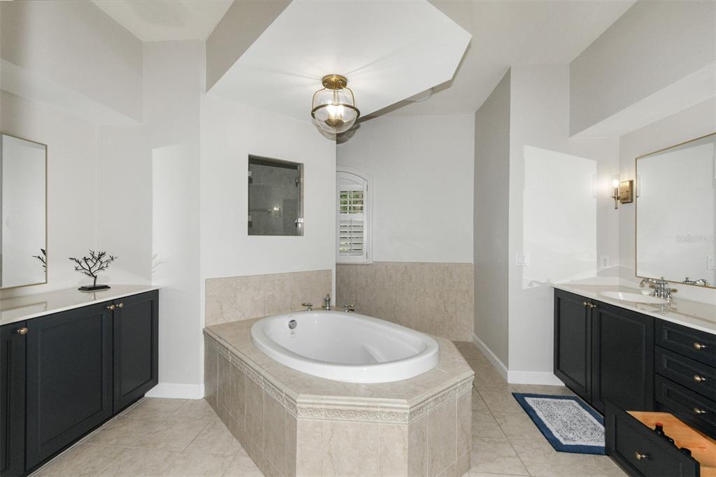 A bathroom features a central soaking tub, dual dark vanities, and beige tile flooring — 1350 N CIRCUS TERRACE, HERNANDO, FL