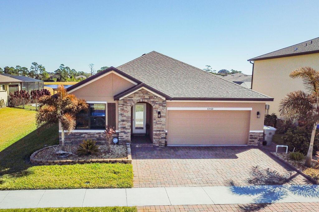 A single-story house with a stone-accented entryway, a two-car garage, and a paved driveway — 6560 Canterbridge Drive, Vero Beach FL 32967, VERO BEACH, FL