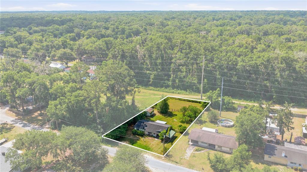An aerial view shows a single-story house with a large backyard and surrounding wooded area — 1504 NE 31ST PLACE, OCALA, FL