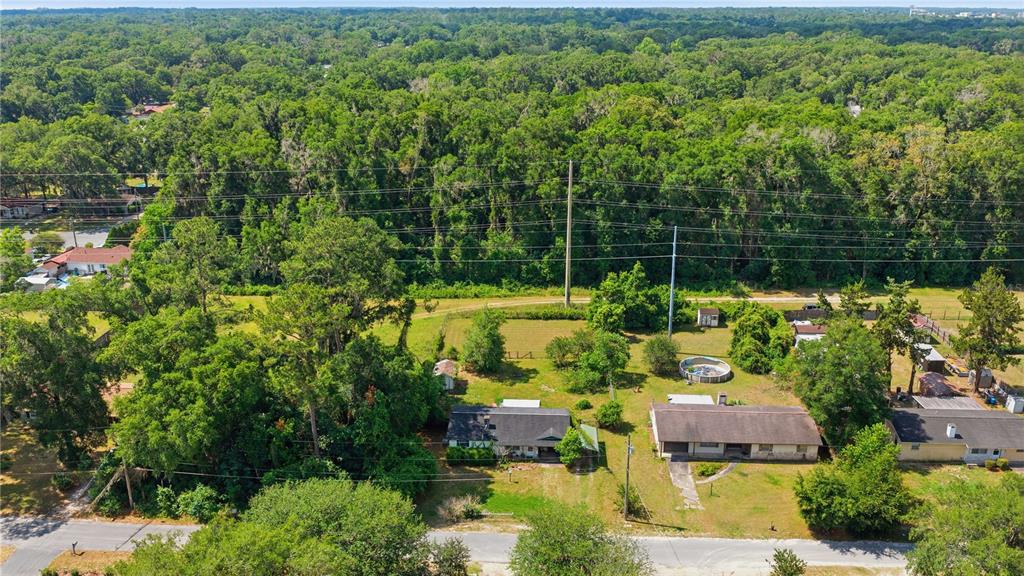 An aerial view shows two houses on a large, grassy lot bordered by dense trees — 1504 NE 31ST PLACE, OCALA, FL