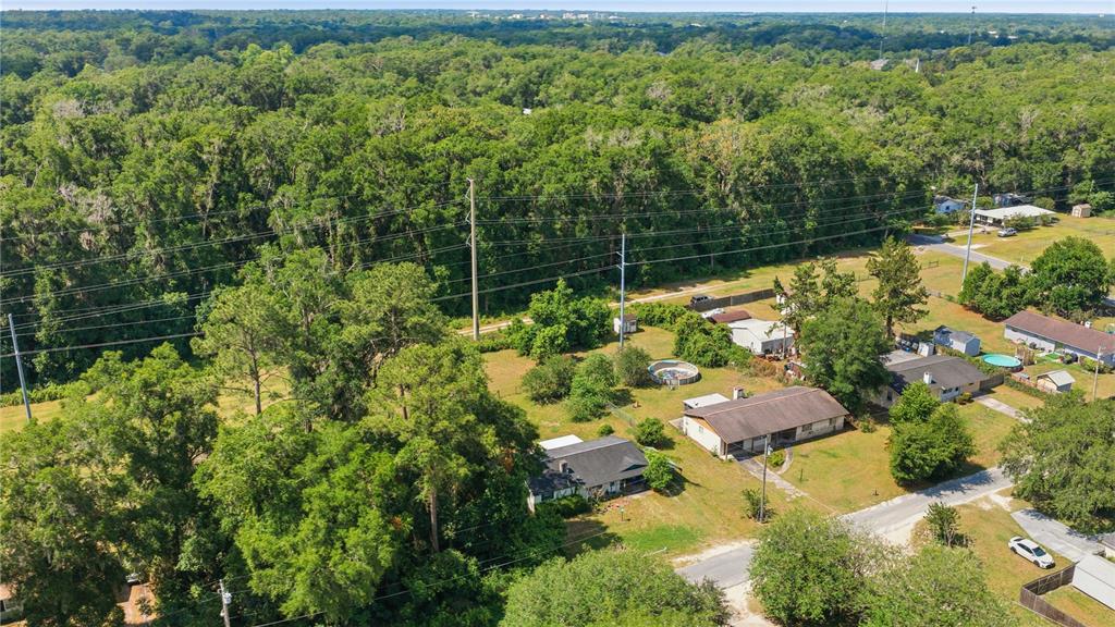 An aerial view shows several houses surrounded by trees and a large power line corridor — 1504 NE 31ST PLACE, OCALA, FL