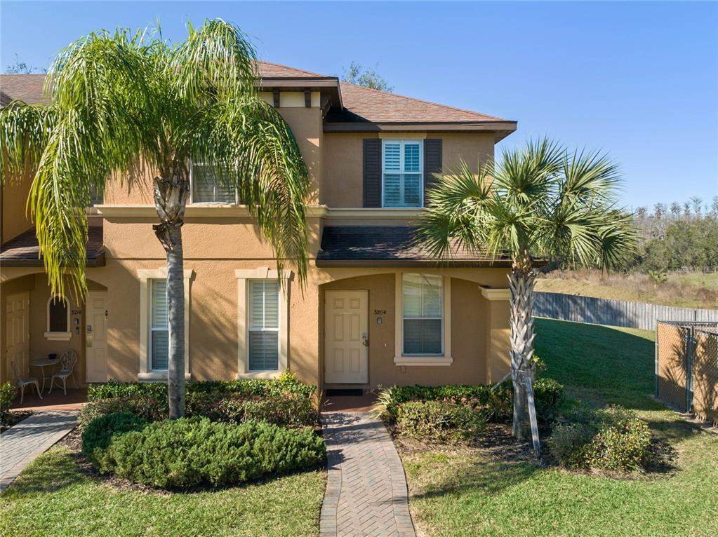 A two-story tan townhouse features a paved walkway, palm trees, and a front entrance — 3204 CALABRIA AVENUE UNIT 3204, DAVENPORT, FL