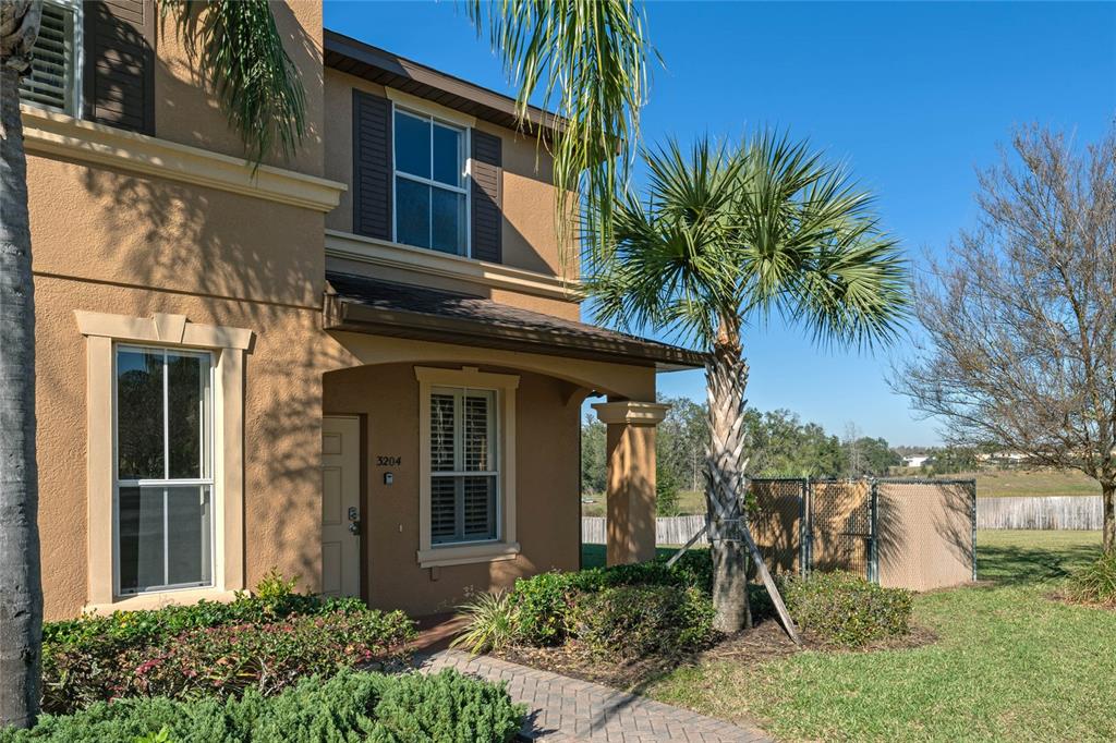 A two-story tan stucco house with a palm tree and a paved walkway — 3204 CALABRIA AVENUE UNIT 3204, DAVENPORT, FL
