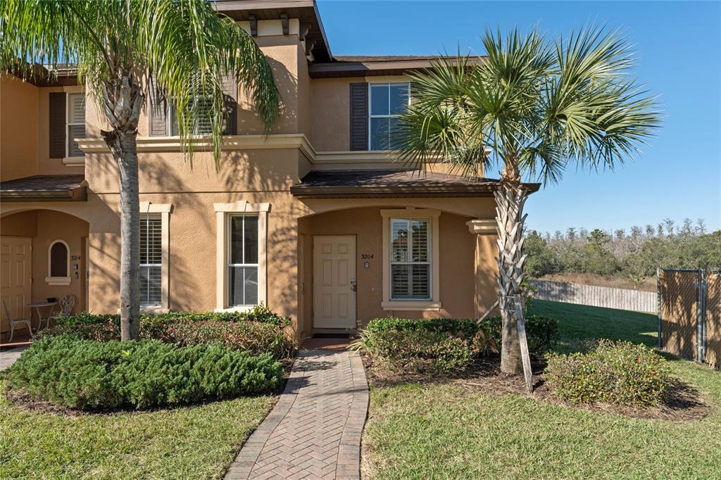 A two-story tan townhouse features a brick walkway, palm trees, and a front entrance — 3204 CALABRIA AVENUE UNIT 3204, DAVENPORT, FL