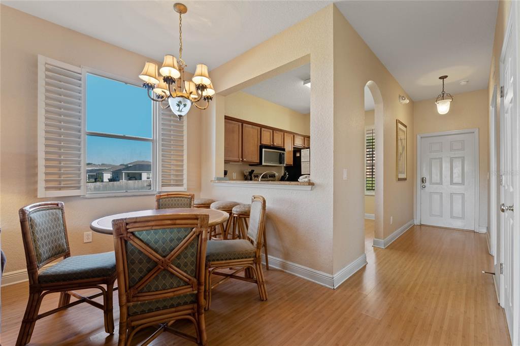 A dining area with a round table and rattan chairs sits beside a kitchen pass-through — 3204 CALABRIA AVENUE UNIT 3204, DAVENPORT, FL