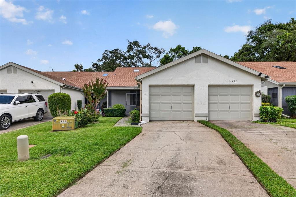 A single-story residential building with two garage doors and a concrete driveway — 11754 SPRING TREE LANE, PORT RICHEY, FL