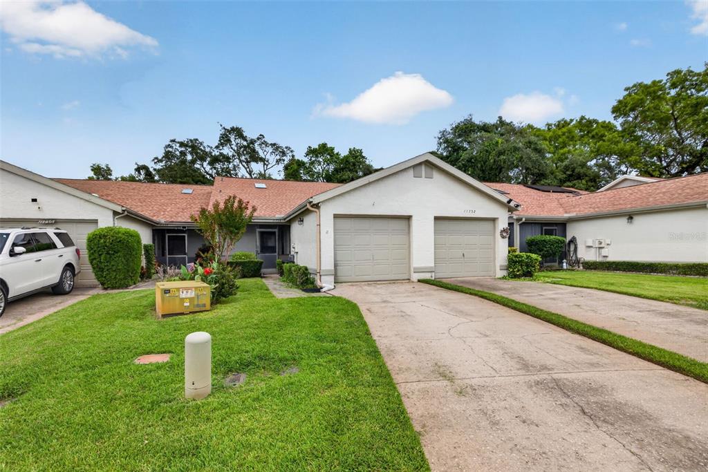 A single-story residential building with two garage doors and a concrete driveway — 11754 SPRING TREE LANE, PORT RICHEY, FL