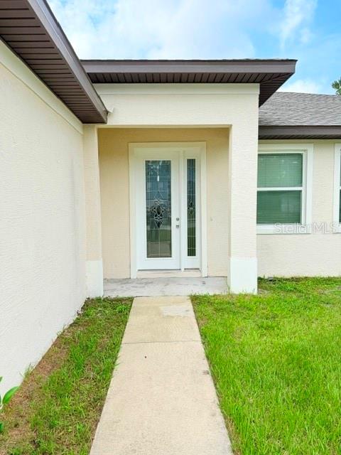A concrete walkway leads to the front entrance of a house with a glass-paneled door — 27 SLUMBER MEADOW TRAIL UNIT A, PALM COAST, FL