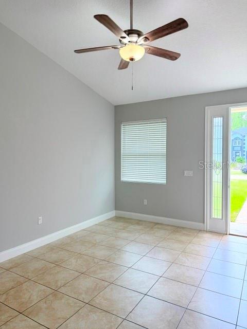 A room with light gray walls, tile flooring, a ceiling fan, and a glass-paneled door — 27 SLUMBER MEADOW TRAIL UNIT A, PALM COAST, FL