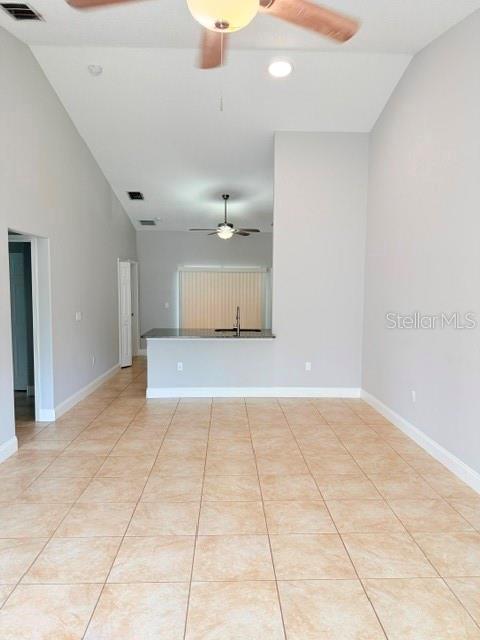A room with light-colored tile flooring, a high ceiling with a fan, and a kitchen counter — 27 SLUMBER MEADOW TRAIL UNIT A, PALM COAST, FL