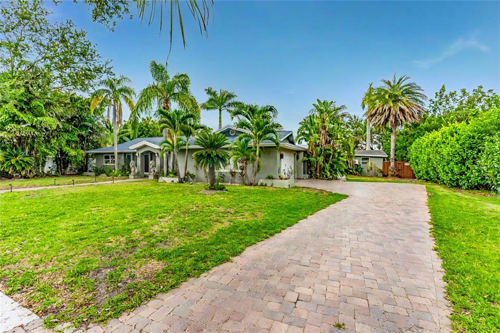 A single-story house with a paved driveway, palm trees, and lush landscaping — 3225 ROSERY ROAD NE, LARGO, FL