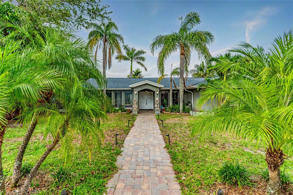 A stone walkway leads to the front entrance of a single-story house with palm trees — 3225 ROSERY ROAD NE, LARGO, FL