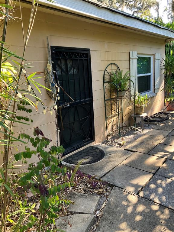 A white sedan is parked under a metal carport attached to a tan garage — 17010 CRAWLEY ROAD, ODESSA, FL