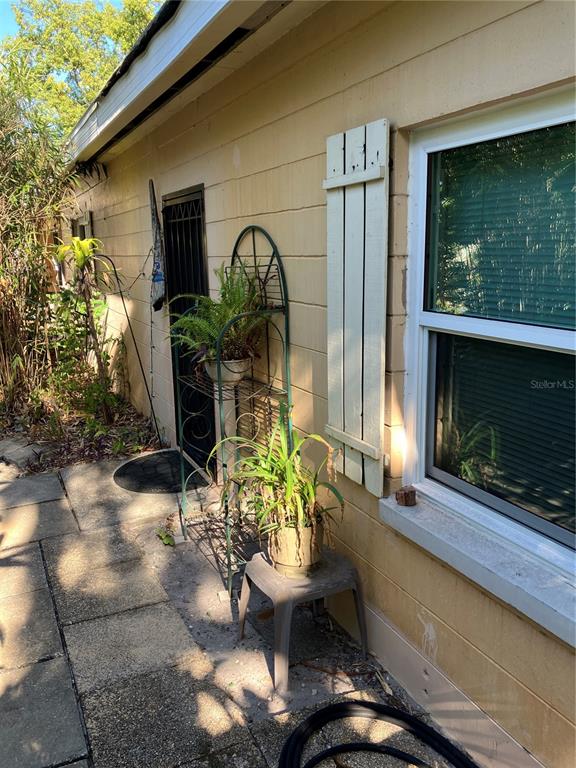 A beige exterior wall features a window with a shutter, a door, and potted plants — 17010 CRAWLEY ROAD, ODESSA, FL