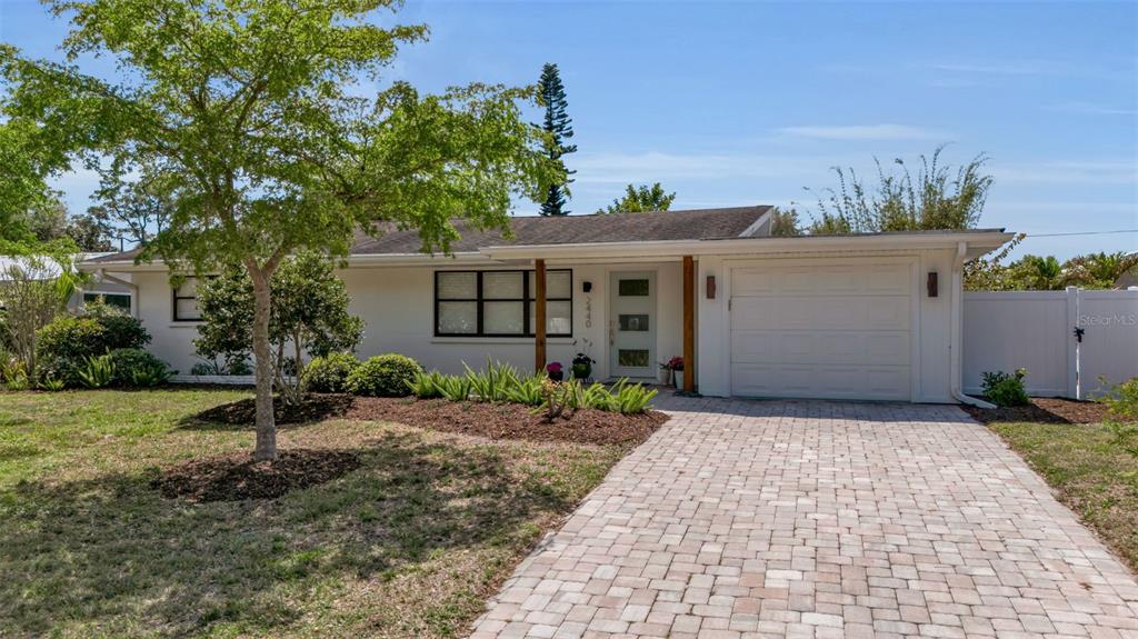 A single-story house with a white exterior, a paver driveway, and a front yard — 2440 VALENCIA DRIVE, SARASOTA, FL