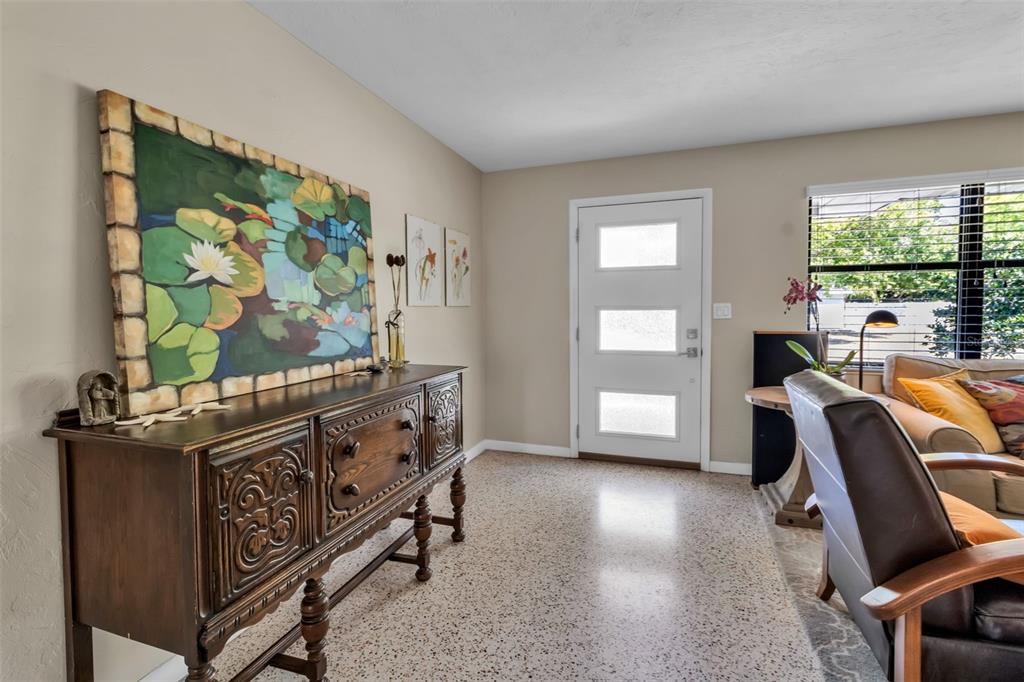 An entryway features a dark wood sideboard, a large lily pad painting, and terrazzo flooring — 2440 VALENCIA DRIVE, SARASOTA, FL