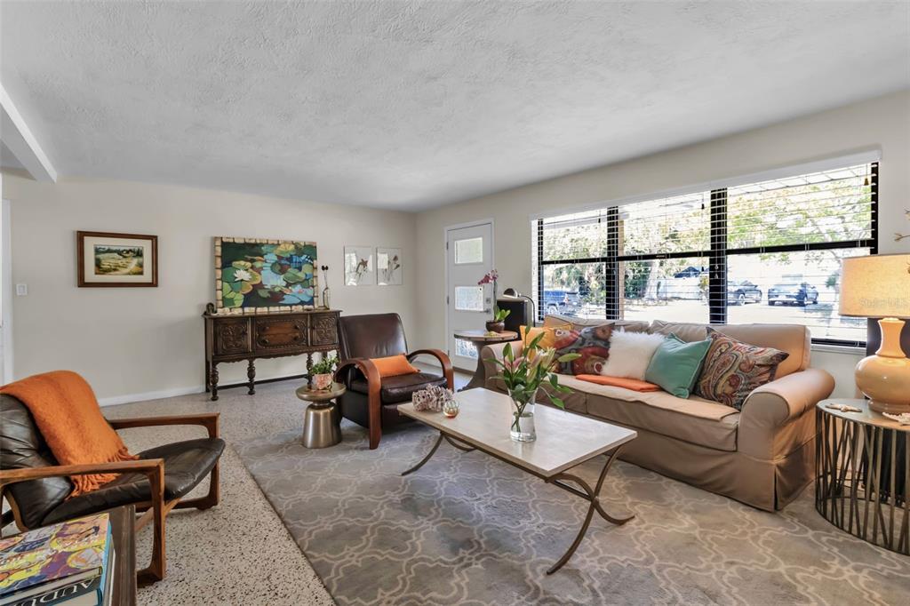 A living room features a beige sofa, leather armchairs, a coffee table, and large windows — 2440 VALENCIA DRIVE, SARASOTA, FL