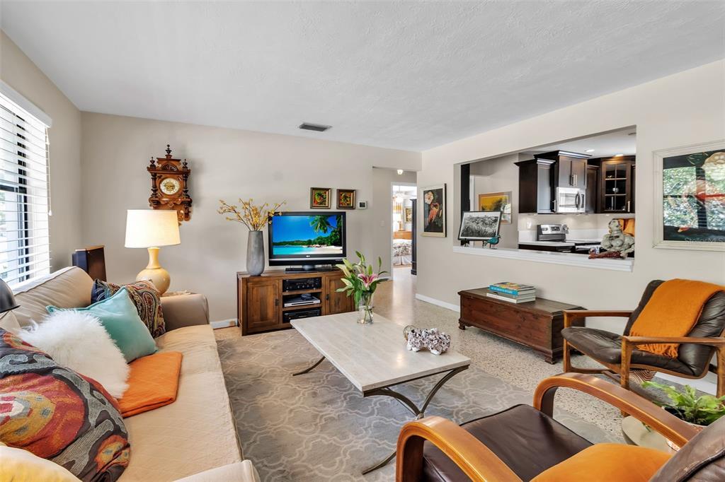 A living room with a beige sofa, two leather chairs, and a kitchen pass-through window — 2440 VALENCIA DRIVE, SARASOTA, FL