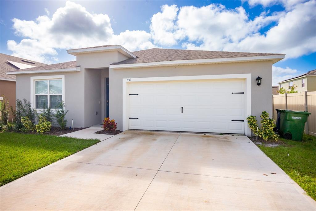 A single-story house with a white garage door, beige stucco exterior, and a concrete driveway — 937 CATTLEMAN STREET, WINTER HAVEN, FL
