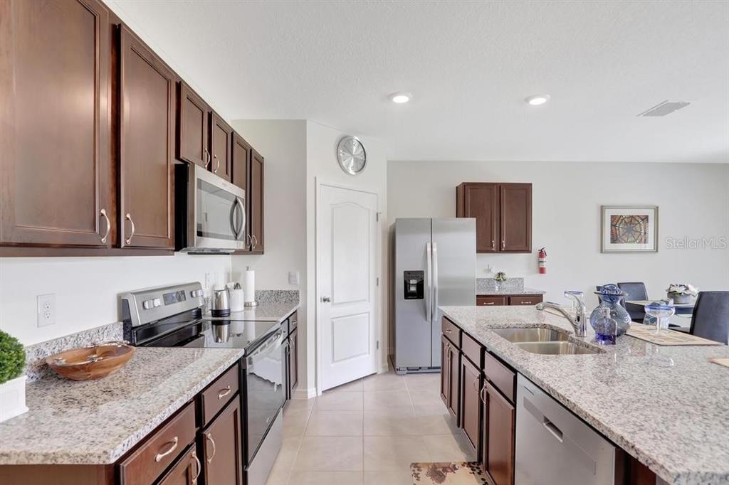 A kitchen features dark wood cabinets, granite countertops, stainless steel appliances, and a central island — 937 CATTLEMAN STREET, WINTER HAVEN, FL