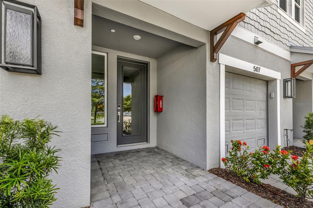 The exterior entrance features a gray front door, a paver walkway, and a garage door — 1617 SEAHAVEN DRIVE UNIT 506, PUNTA GORDA, FL