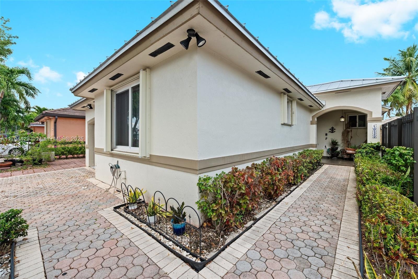 A paved walkway leads to the entrance of a white house with a landscaped garden — 7045 SW 161 PL, Miami FL 33193, MIAMI, FL