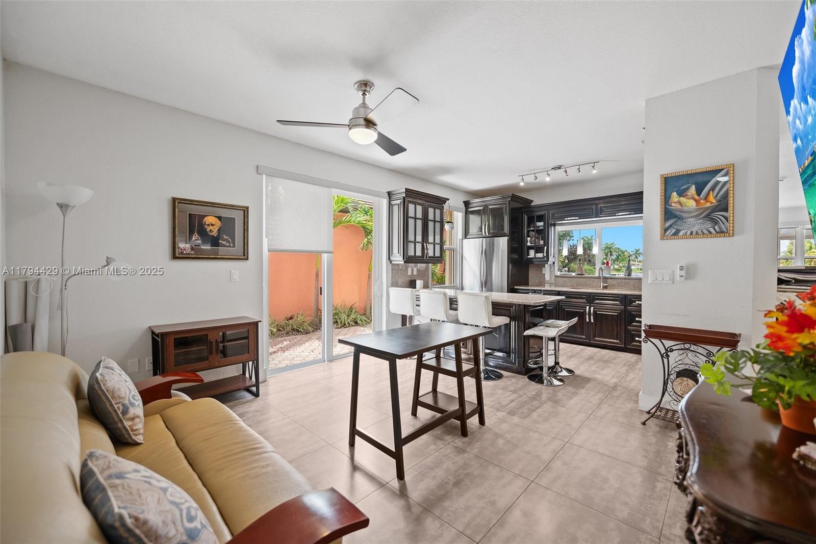 A living room with a beige sofa connects to an open kitchen with dark cabinetry — 7045 SW 161 PL, Miami FL 33193, MIAMI, FL
