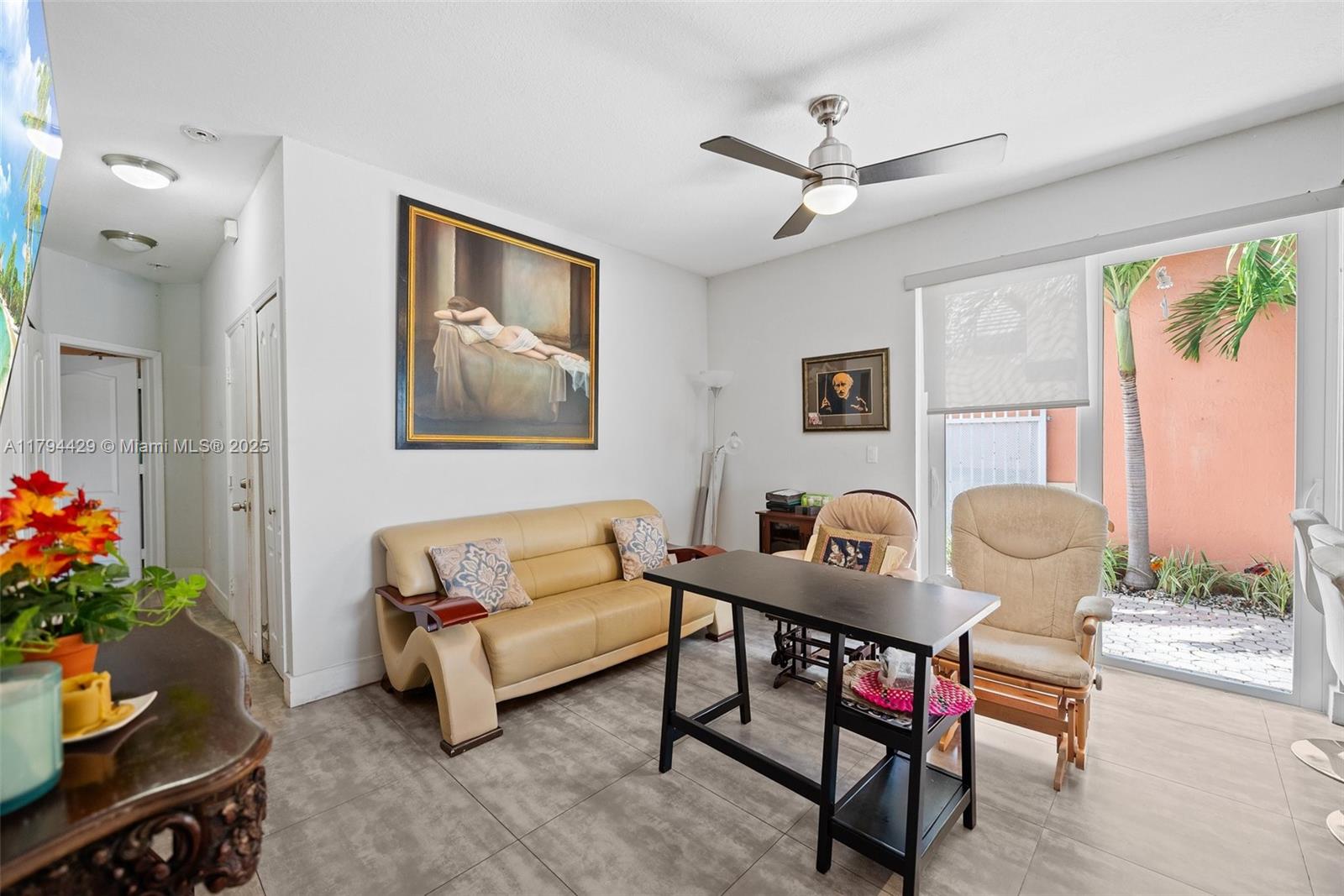 A living room features a beige sofa, a black table, and a sliding glass door — 7045 SW 161 PL, Miami FL 33193, MIAMI, FL