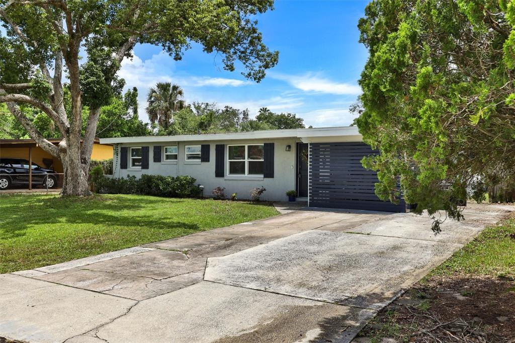 A single-story house with a gray exterior, a concrete driveway, and a large front tree — 732 LOGAN DRIVE, LONGWOOD, FL