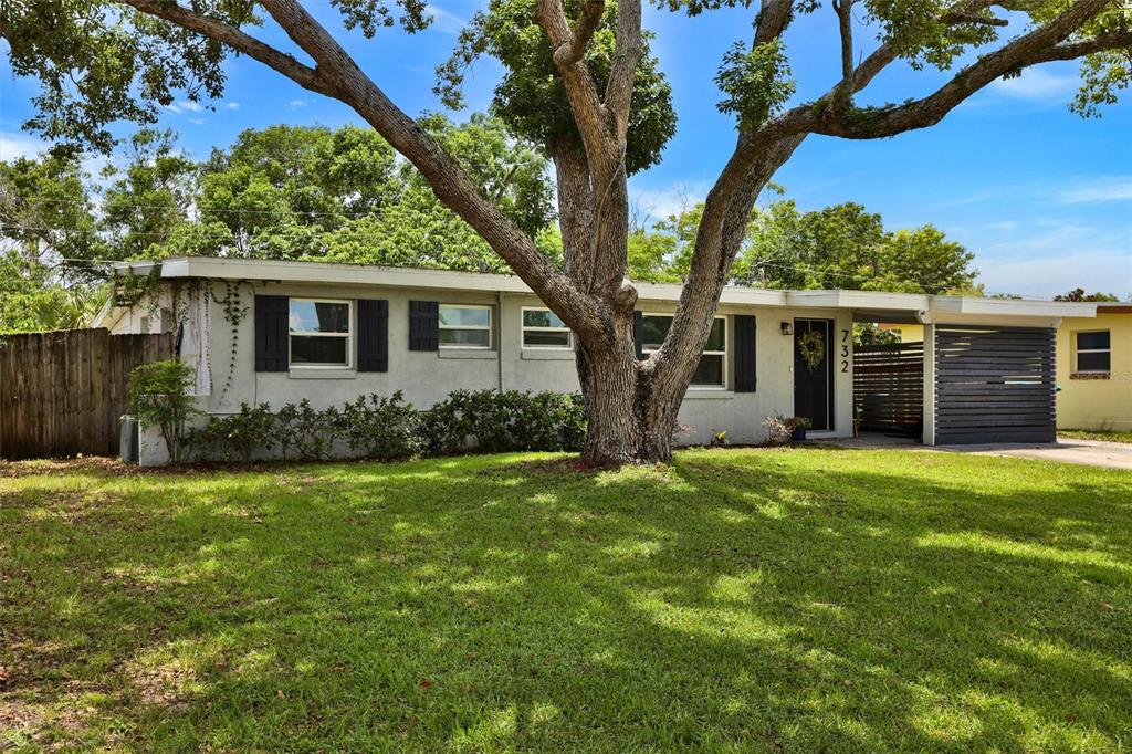 A single-story house with a large tree in the front yard and a carport — 732 LOGAN DRIVE, LONGWOOD, FL