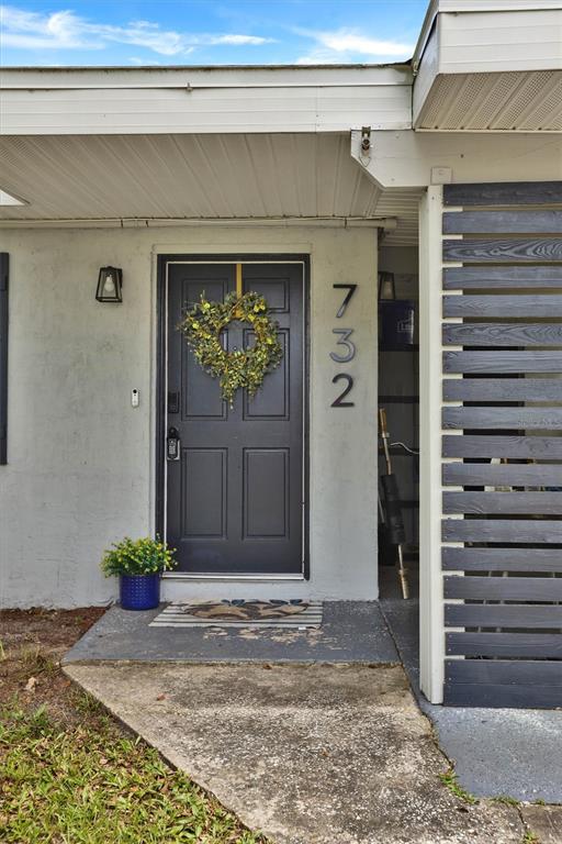 The exterior view shows a dark front door with a wreath and house numbers — 732 LOGAN DRIVE, LONGWOOD, FL